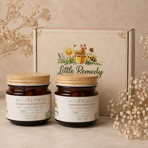 Two jars of 'Little Remedy' garlic fermented honey with a decorative box in the background.